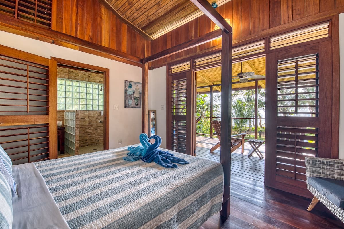 A room with a bed, a chair, and a view of the outdoors.