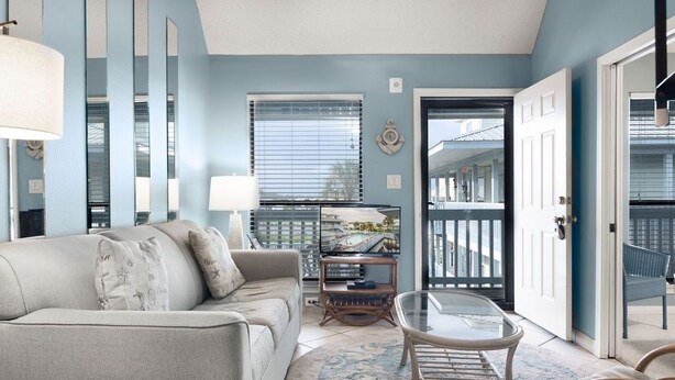 A living room with a sofa, a glass coffee table, and a TV on a stand. - The Cove 217a 1 Bedroom Condo by RedAwning (Gulf Shores)