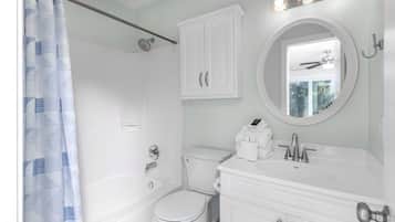 A bathroom with a shower, toilet, and vanity with a mirror.