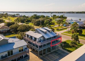 A waterfront property with a two-story building featuring balconies and a covered outdoor area. - Sandy Shores West 101 2 Bedroom Condo by RedAwning (Gulf Shores)