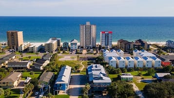 Zona residencial costera con casas unifamiliares y edificios de apartamentos, una calle y una playa al fondo.