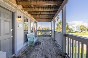A covered porch with a bench, a door, and a view of the neighborhood. - Sandy Shores West 101 2 Bedroom Condo by RedAwning (Gulf Shores)