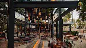 An outdoor dining area with tables and chairs, a wooden floor, and hanging lights.