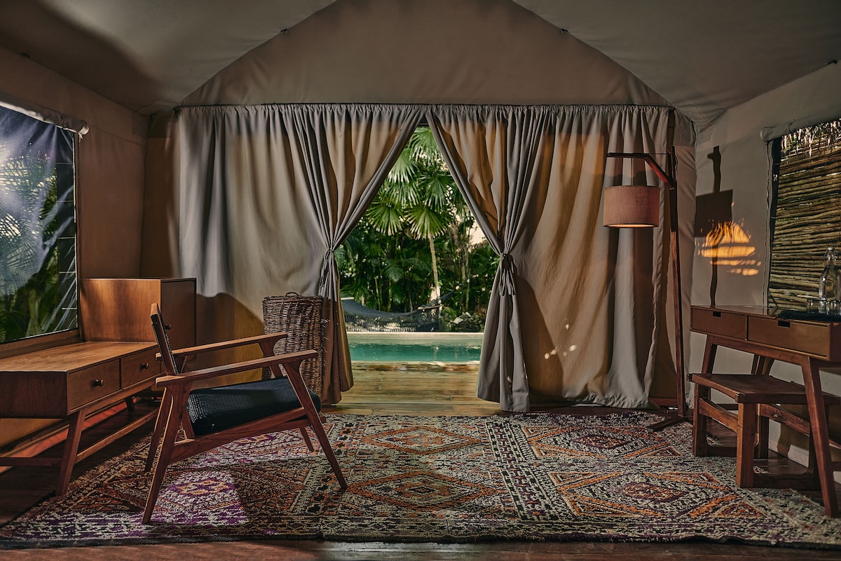 inside the tent of OurHabitas Tulum, with chairs and lamps, and a private pool outside