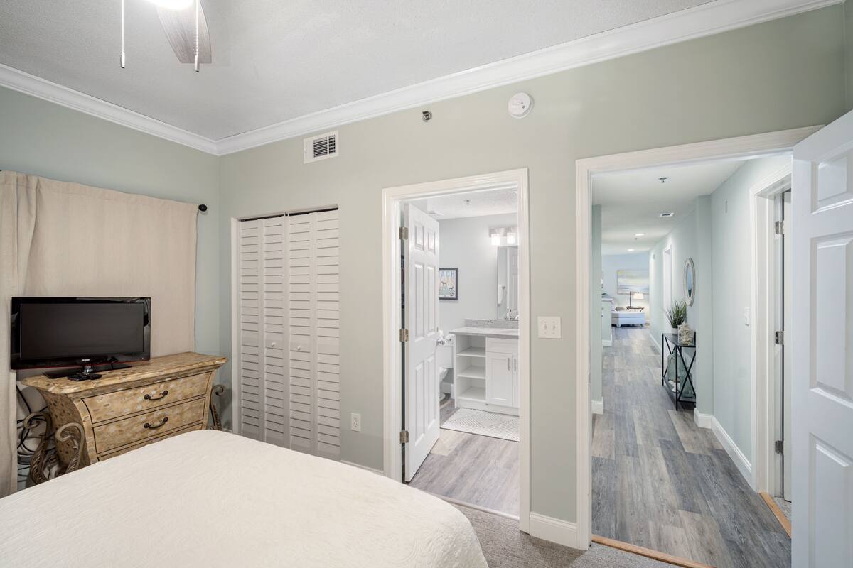 A bedroom with a bed, a dresser, a television, and a closet.