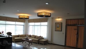A spacious living room with a large sofa, a coffee table, and two pendant lights. - QG Resort (Bangkok)