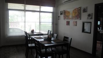 A dining area with a large window, a table with chairs, and wall-mounted artwork.