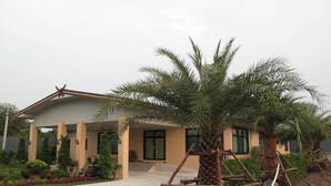 A modern house with a covered porch, palm trees, and a well-maintained garden. - QG Resort (Bangkok)