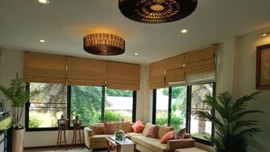 A spacious living room with large windows, a sofa set, a coffee table, and a decorative floor pattern. - QG Resort (Bangkok)