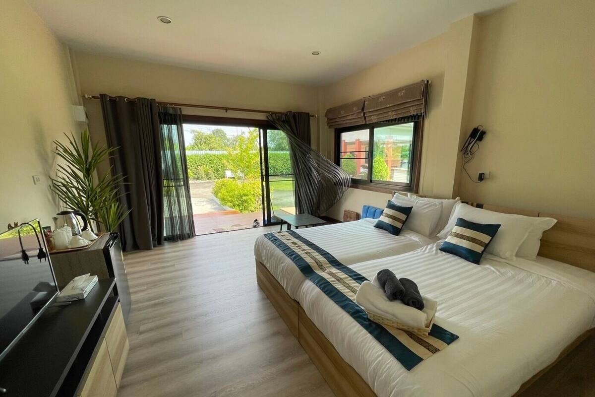 A hotel room with two beds, a desk, and a view of the outdoors.