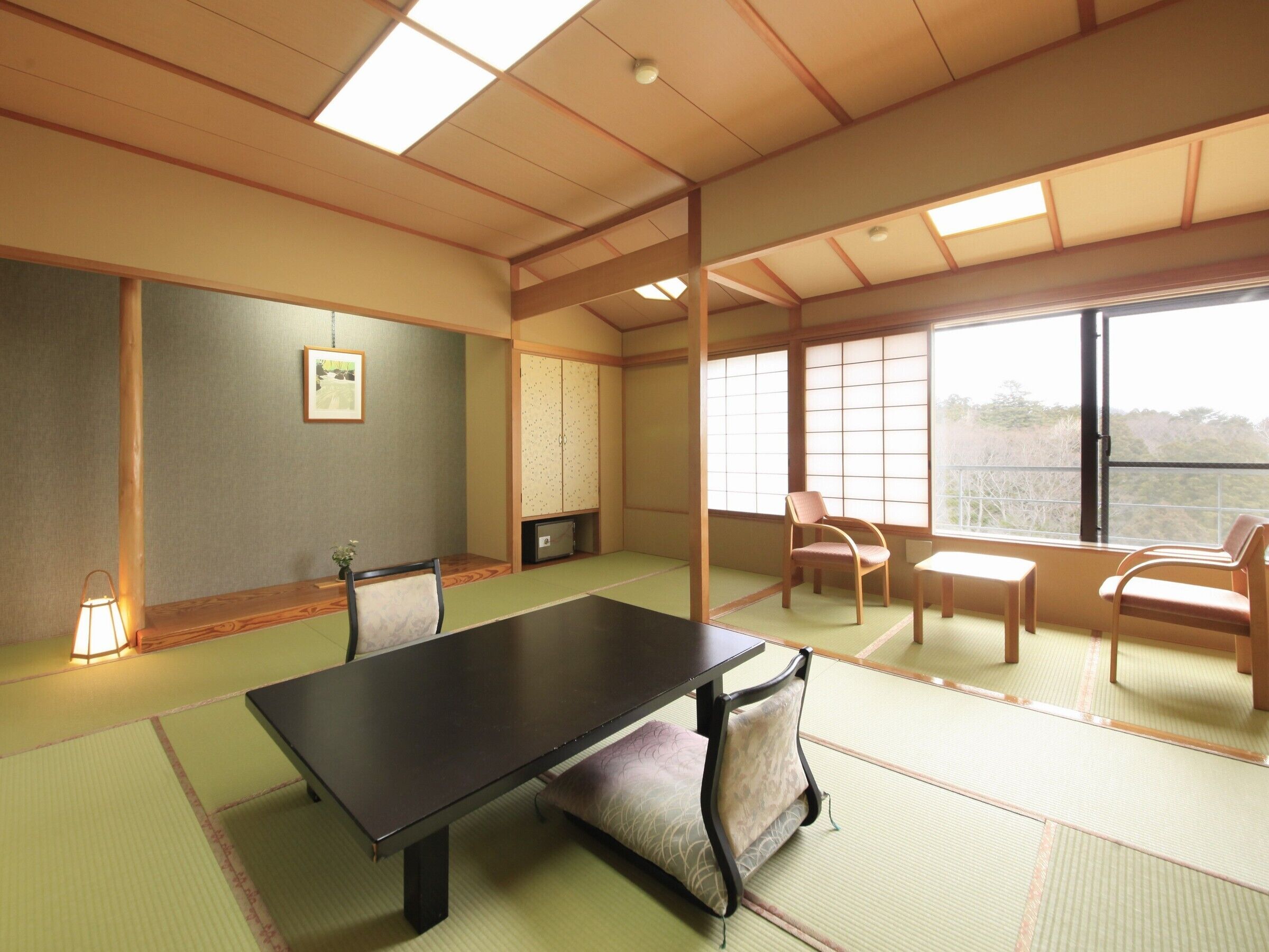 A tatami mat room with a low table, chairs, a cabinet, and a window.