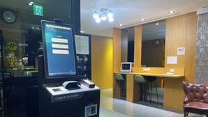 A hotel reception area with a digital check-in kiosk, a wooden reception desk, and a leather chair. - The Koos Hotel Dahu (Taipei)