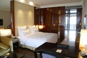 Una habitación de hotel con una cama grande, lámparas de noche, un escritorio con teléfono y una silla.