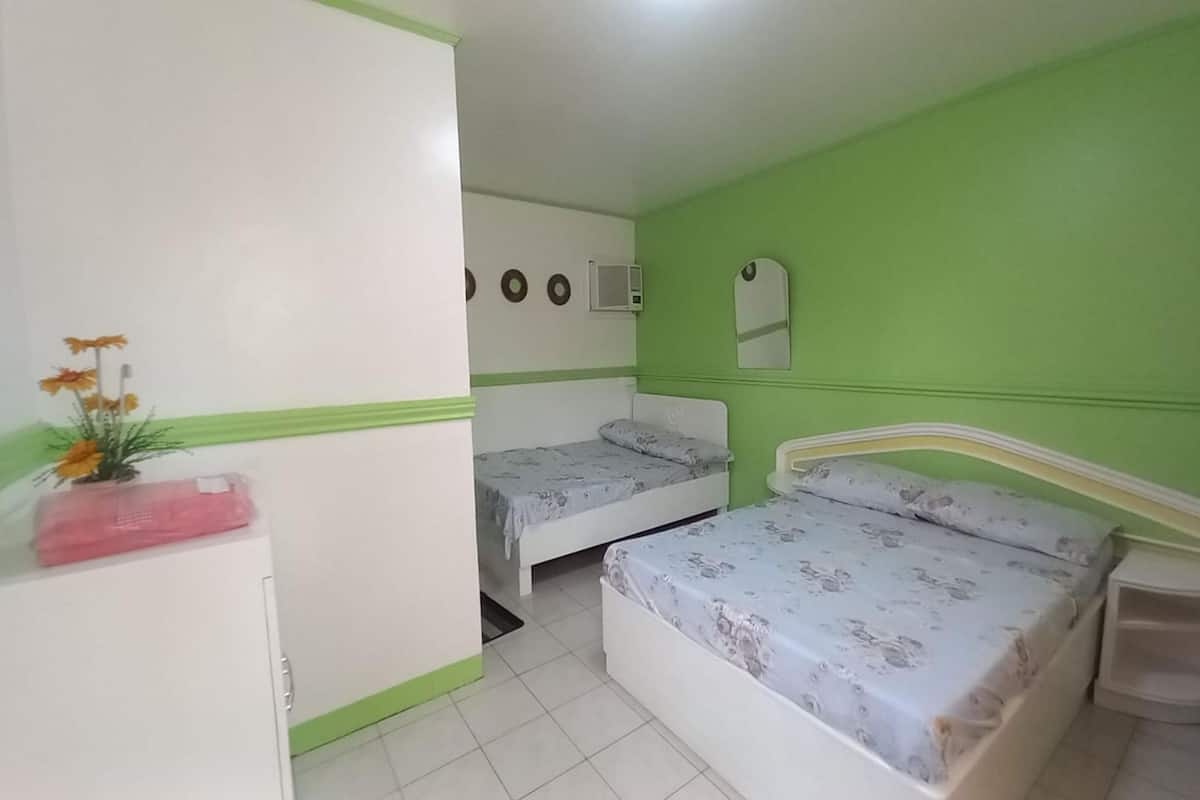 A room with two beds, a small cabinet, a mirror, and a wall with circular decorations.