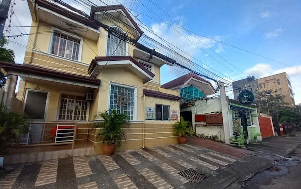 Un edificio de dos pisos con entrada de baldosas y plantas en macetas.