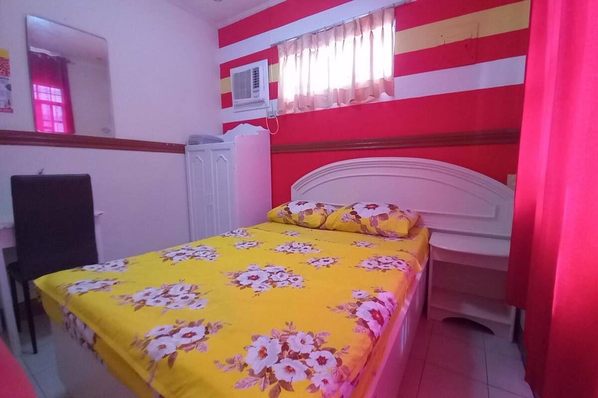A bedroom with a bed, a wardrobe, and an air conditioning unit.
