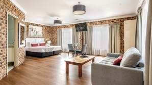 Een moderne hotelkamer met een bakstenen muur, een bed, een sofa, een salontafel en een televisie.