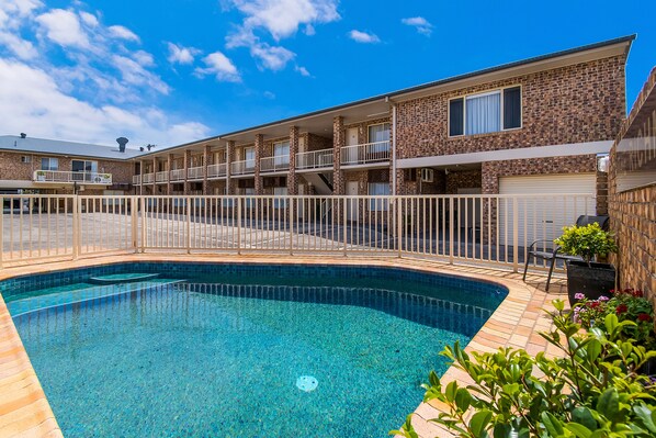 Un motel con piscina, varios balcones y fachada de ladrillo.