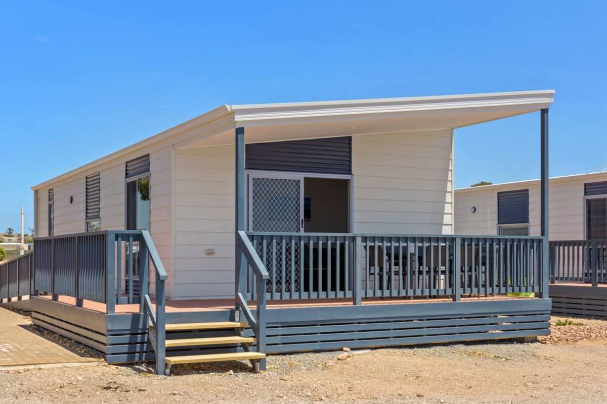 Une maison mobile de plain-pied, dotée d’un porche couvert et d’un petit escalier menant à l’entrée.