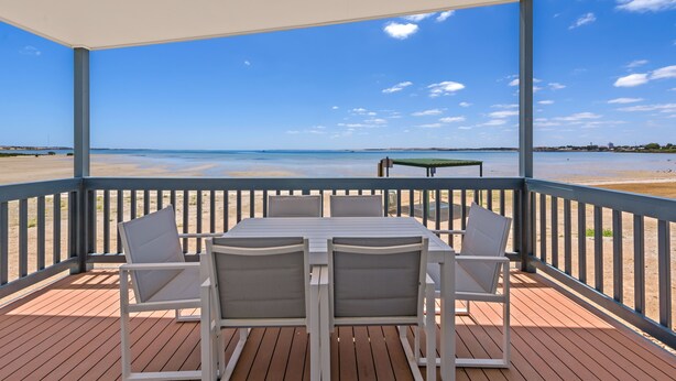 A covered outdoor seating area with a table and chairs, overlooking a beach. - Discovery Parks - Streaky Bay Foreshore (Streaky Bay)