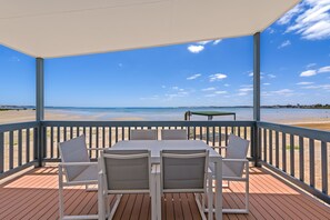 Un espacio de estar techado al aire libre con una mesa y sillas, con vista a la playa.