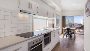 A modern kitchen with white cabinets, a stainless steel range, and a large window overlooking a balcony. - Discovery Parks - Streaky Bay Foreshore (Streaky Bay)