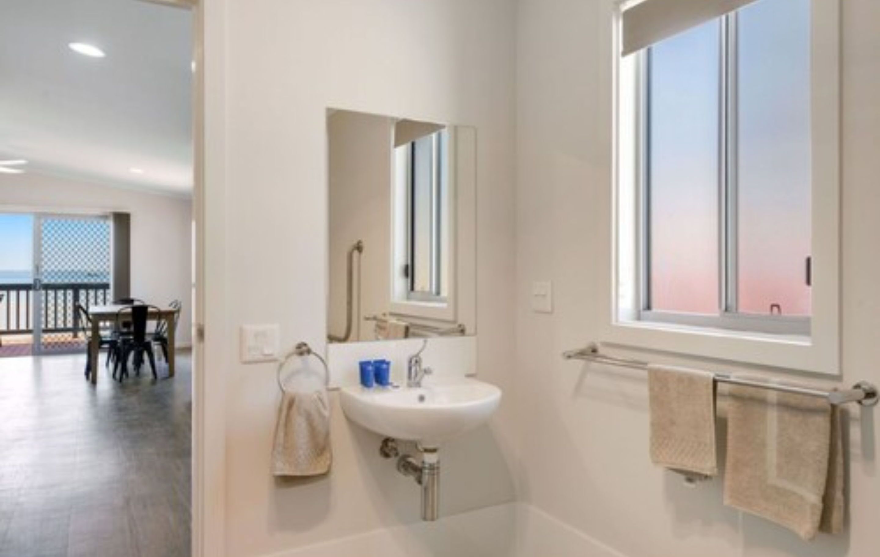 Ein modernes Badezimmer mit Waschbecken, Spiegel und Handtuchhalter.