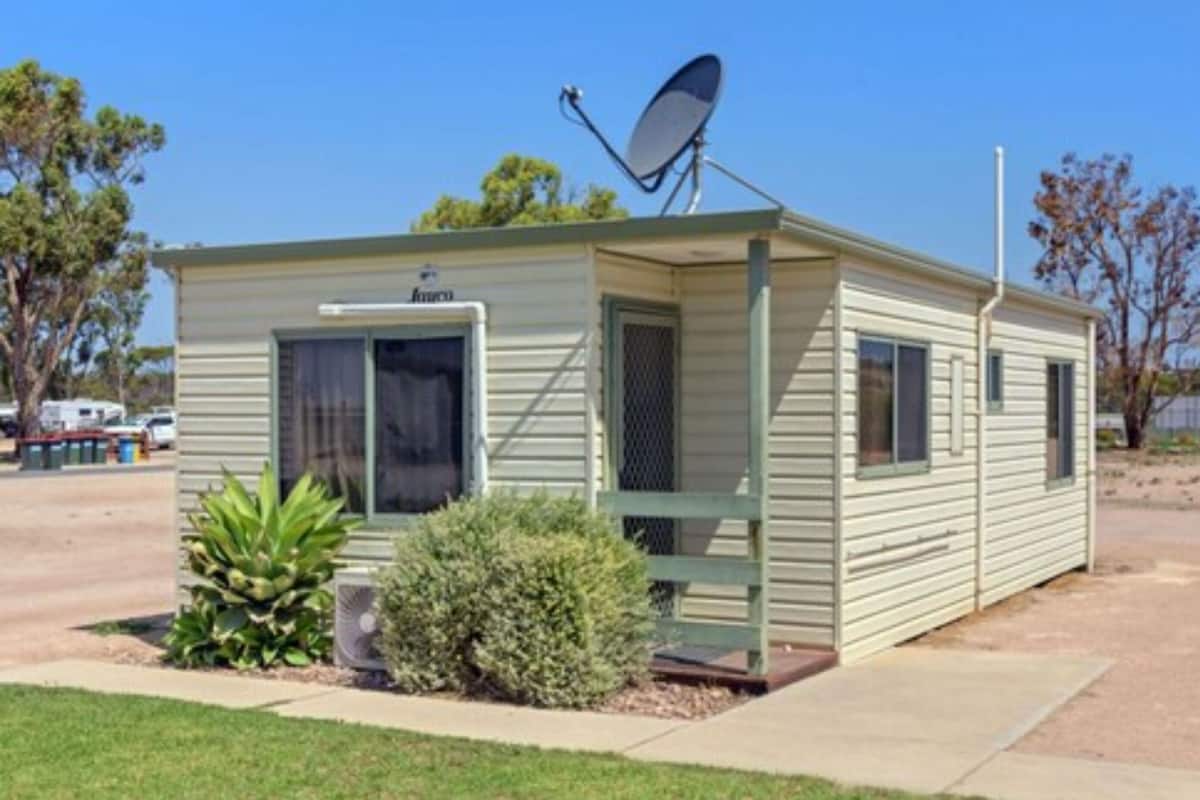 Une maison mobile de plain-pied, dotée d’une antenne parabolique, d’un petit porche et d’une porte d’entrée.
