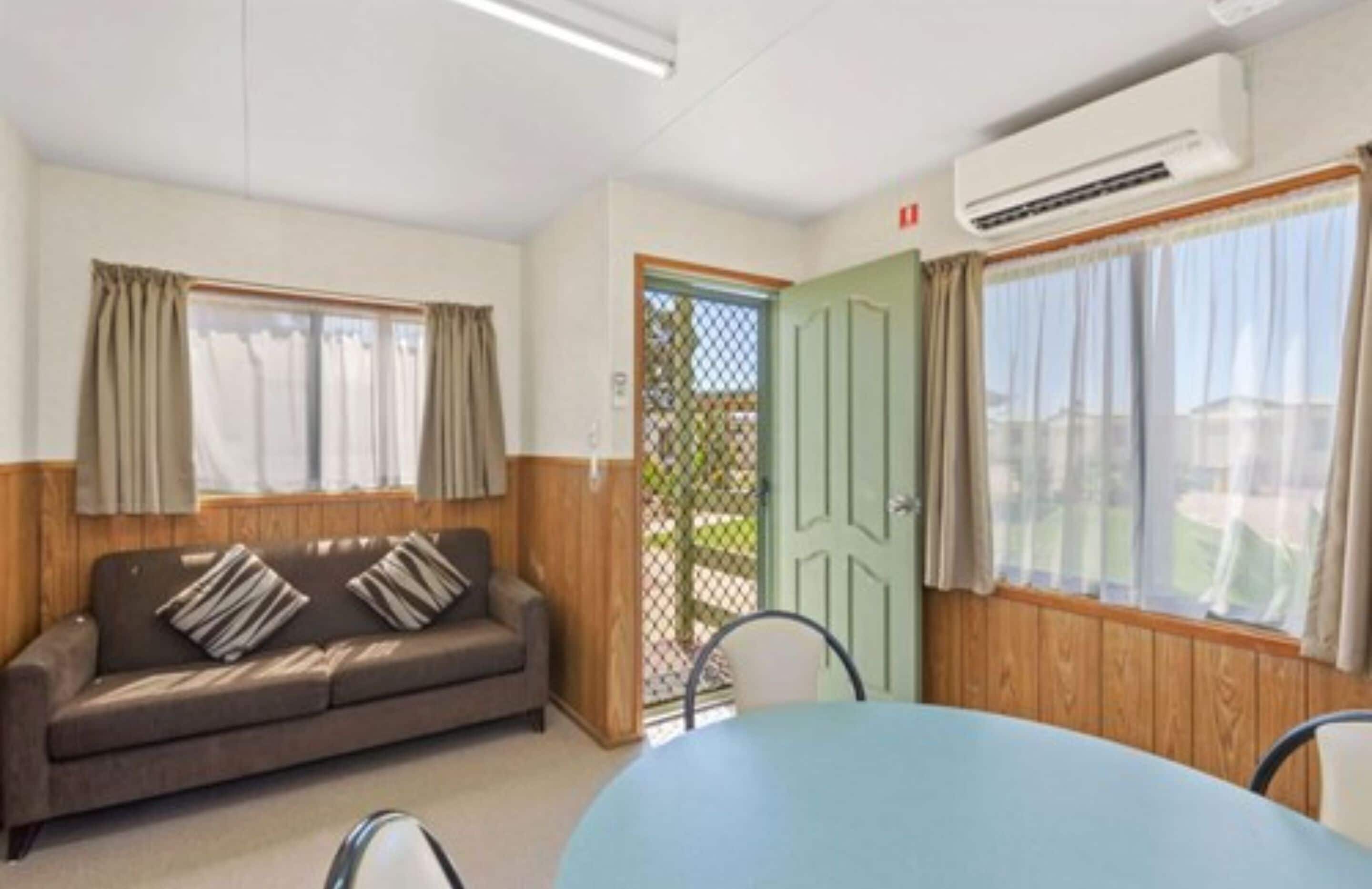 A room with a sofa, a table, and a door leading outside.