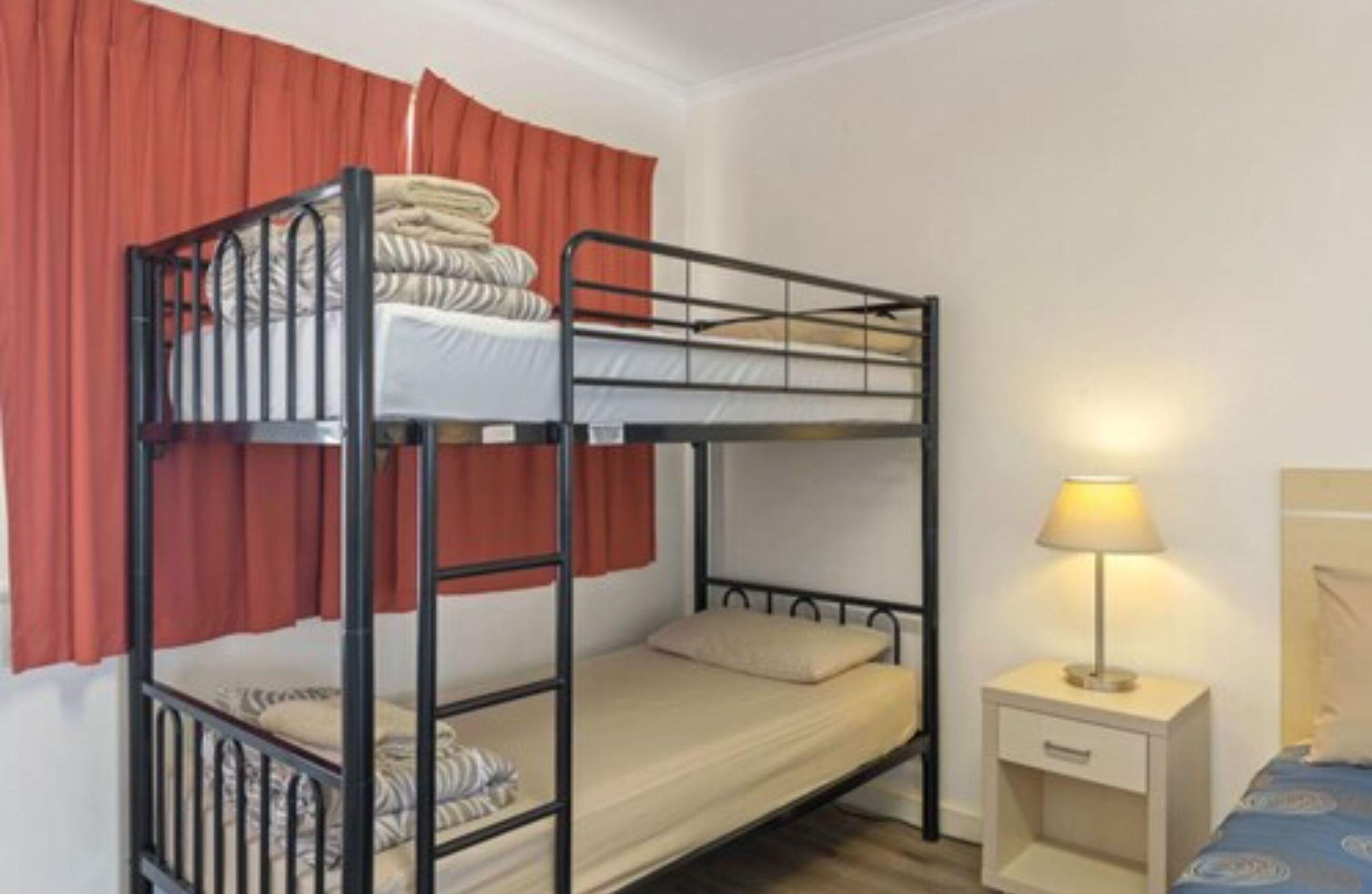 A bunk bed room with a nightstand and a lamp.