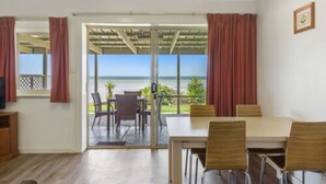 A room with a table and chairs, a television, and a view of the ocean through large windows. - Discovery Parks - Streaky Bay Foreshore (Streaky Bay)
