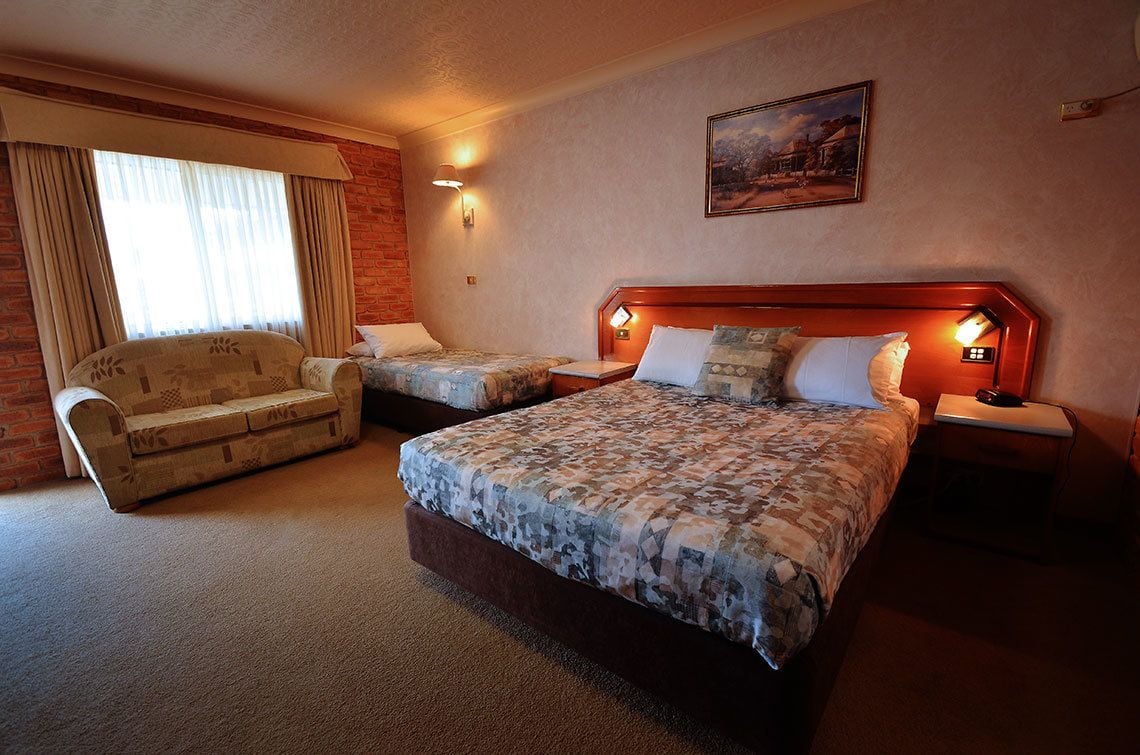 Une chambre d’hôtel avec un grand lit, un lit plus petit, un canapé et un bureau.