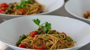 A bowl of noodles with vegetables and a garnish.