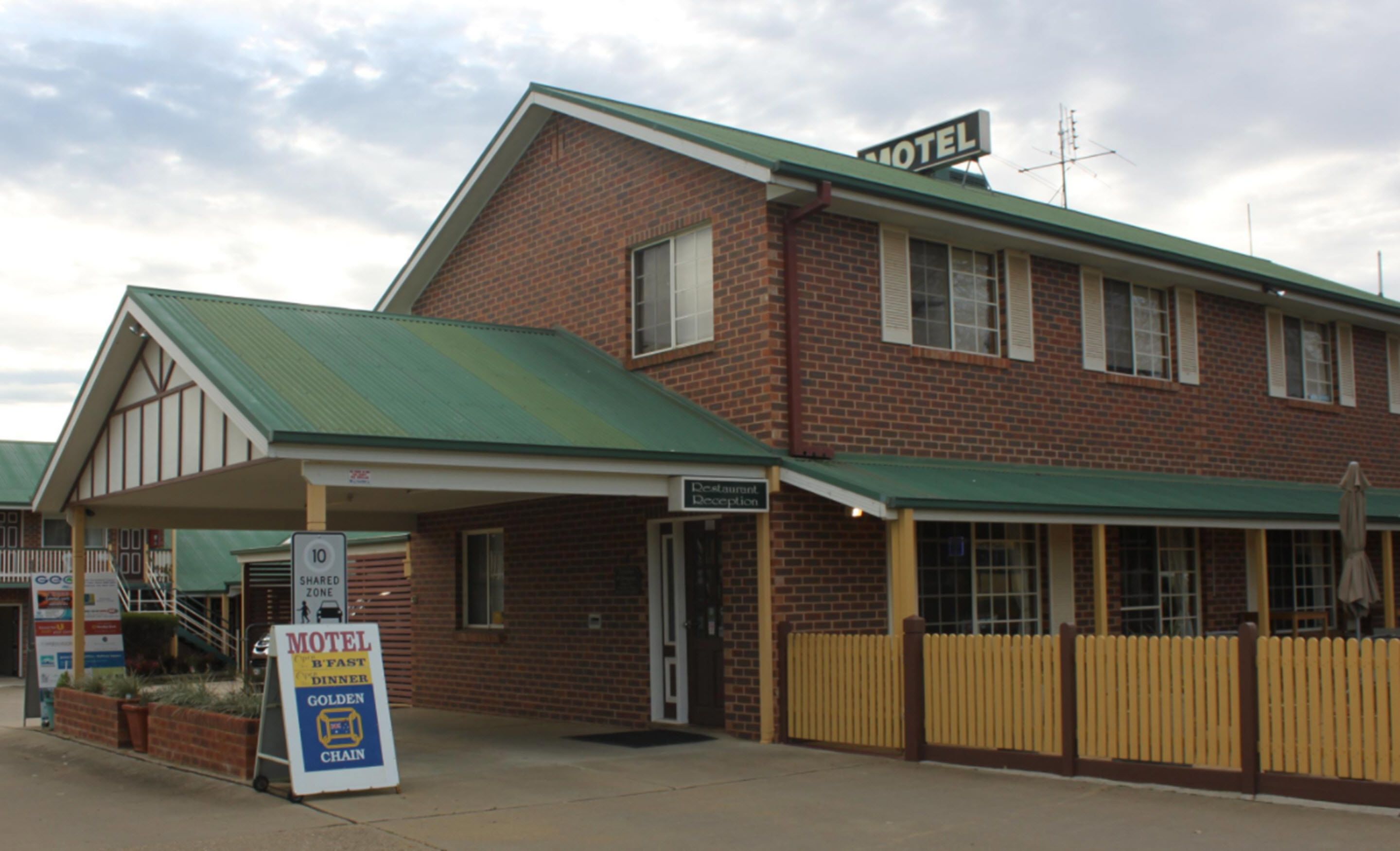A motel with a green roof, a reception area, and a sign indicating a shared zone.