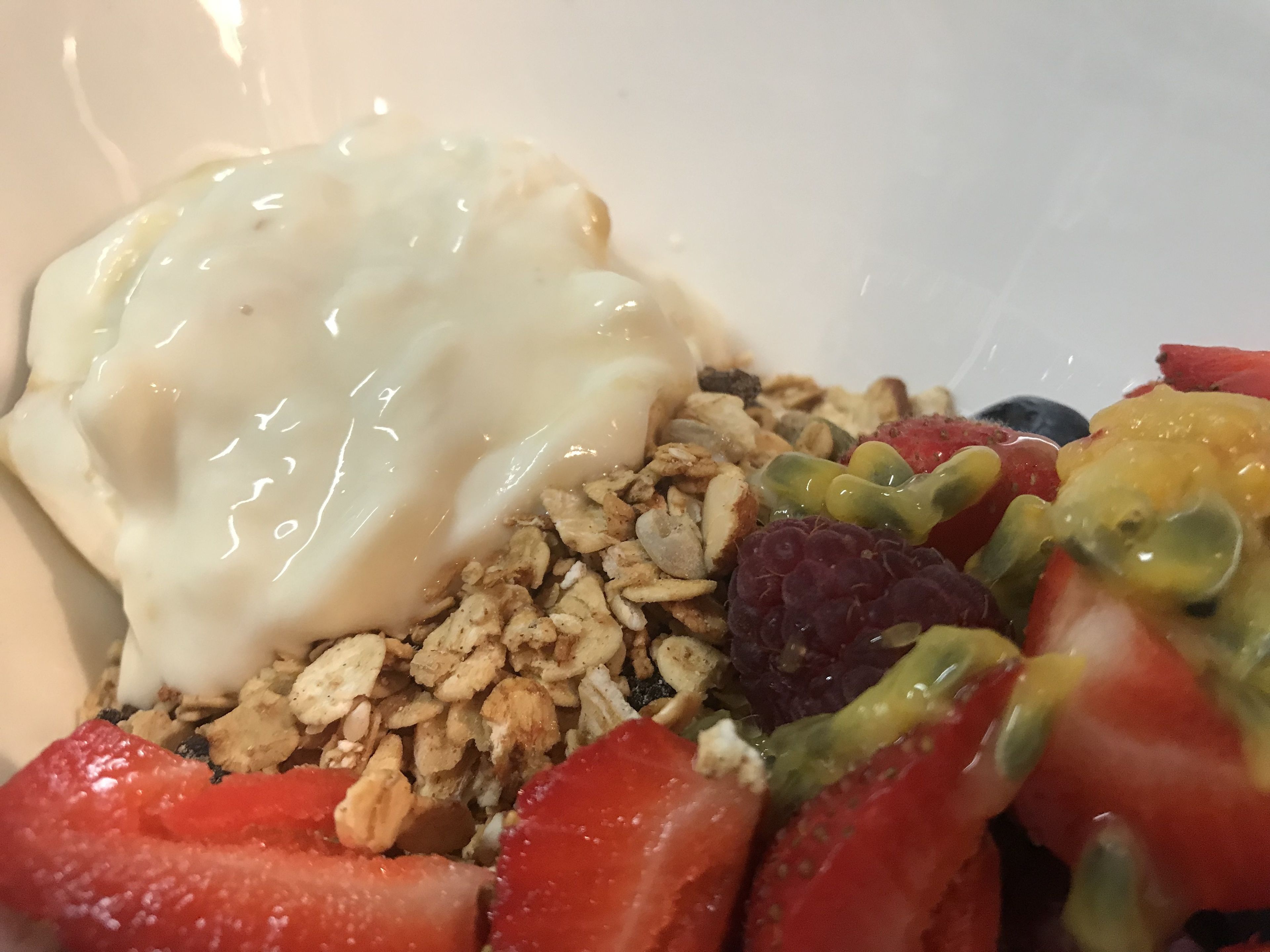 A bowl of cereal with strawberries, blueberries, and a dollop of yogurt.