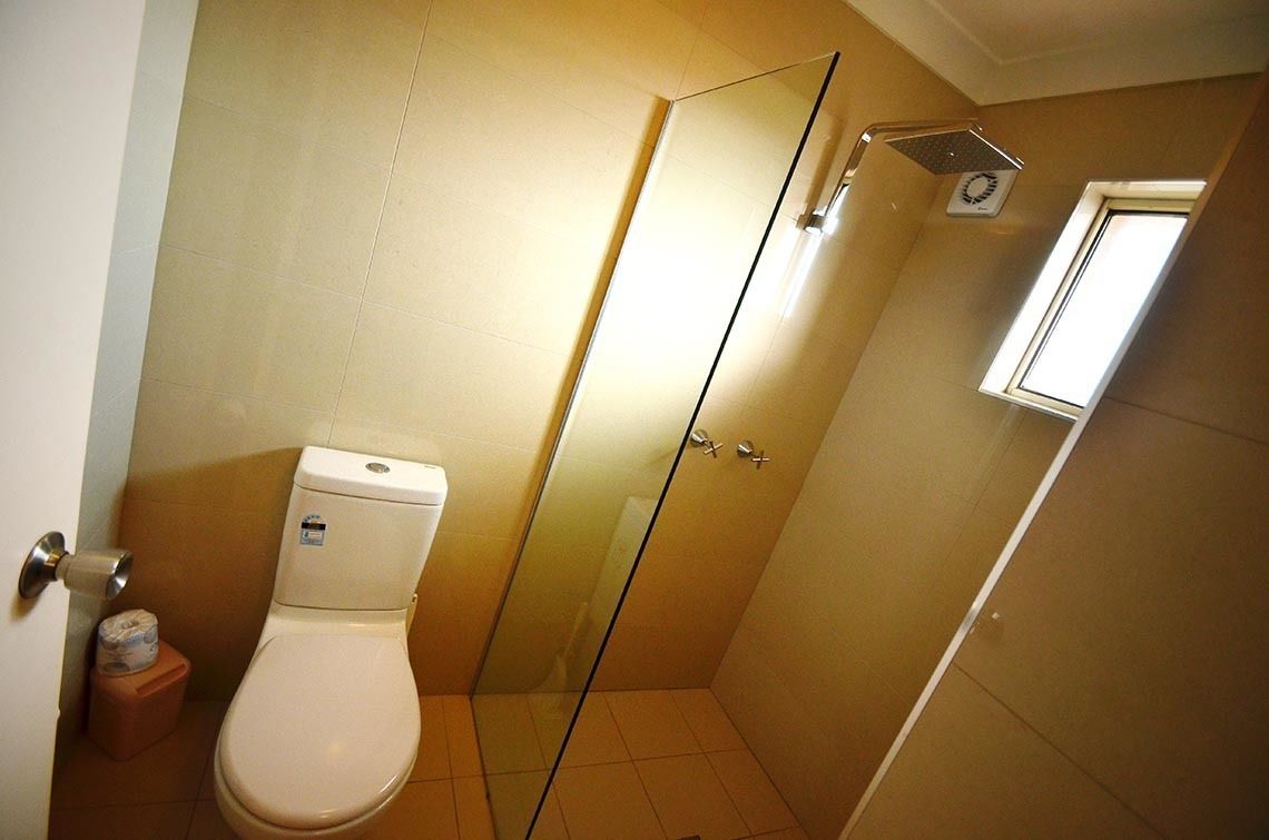 Une salle de bain avec des toilettes, une douche à parois de verre et une petite fenêtre.