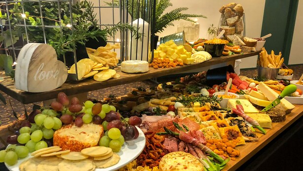 A buffet with various cheeses, fruits, and meats.