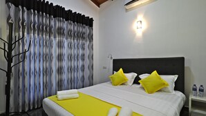 Une chambre d’hôtel avec un lit, une table de chevet, une lampe et une fenêtre avec des rideaux.