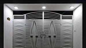 Une entrée fermée par un portail en métal orné de motifs géométriques et d’un motif circulaire central.