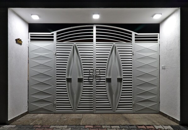 Una entrada protegida por una reja metálica con diseños geométricos y un motivo circular central.