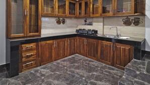 Une cuisine avec des meubles en bois, un plan de travail noir et un pare-feu en carrelage.