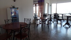 Un espace repas comprenant plusieurs tables et chaises, un réfrigérateur et une fenêtre avec des rideaux.