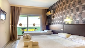 A hotel room with two beds, a balcony view, and a patterned wall. - Green Gold Hotel (Kusadasi)