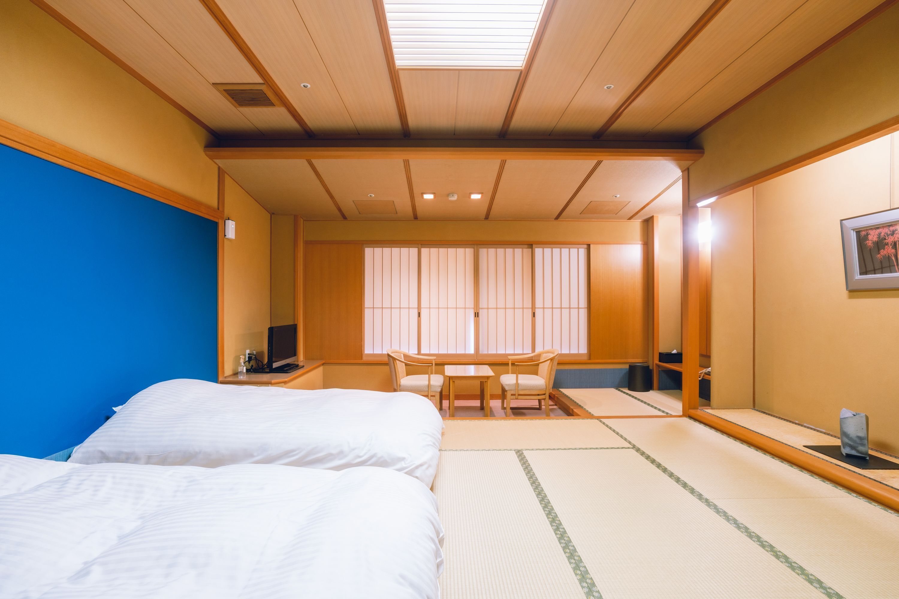 A traditional Japanese room with tatami flooring, a bed, a desk, and a chair.