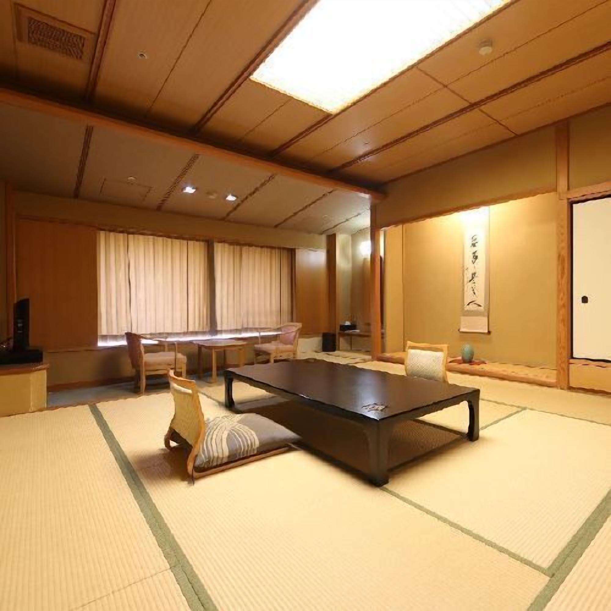A tatami mat room with a low table and chairs, a sliding door, and a traditional Japanese calligraphy on the wall.