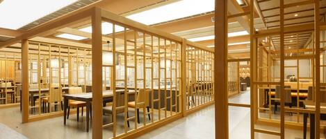 A spacious library with wooden partitions and multiple tables and chairs.