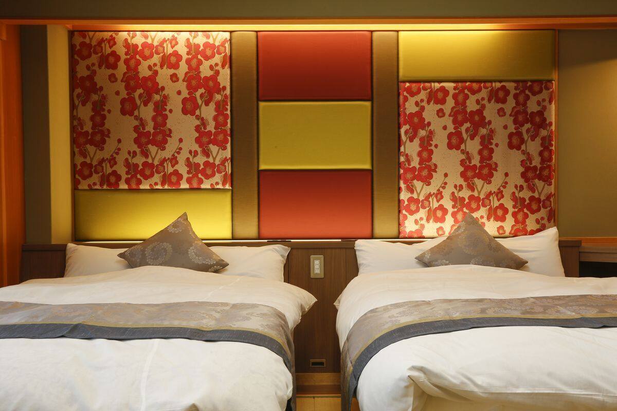 A hotel room with two beds, a decorative headboard, and a nightstand.