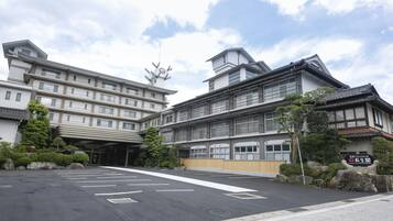A multi-story hotel with a traditional architectural style, featuring a large entrance and a parking area in front.
