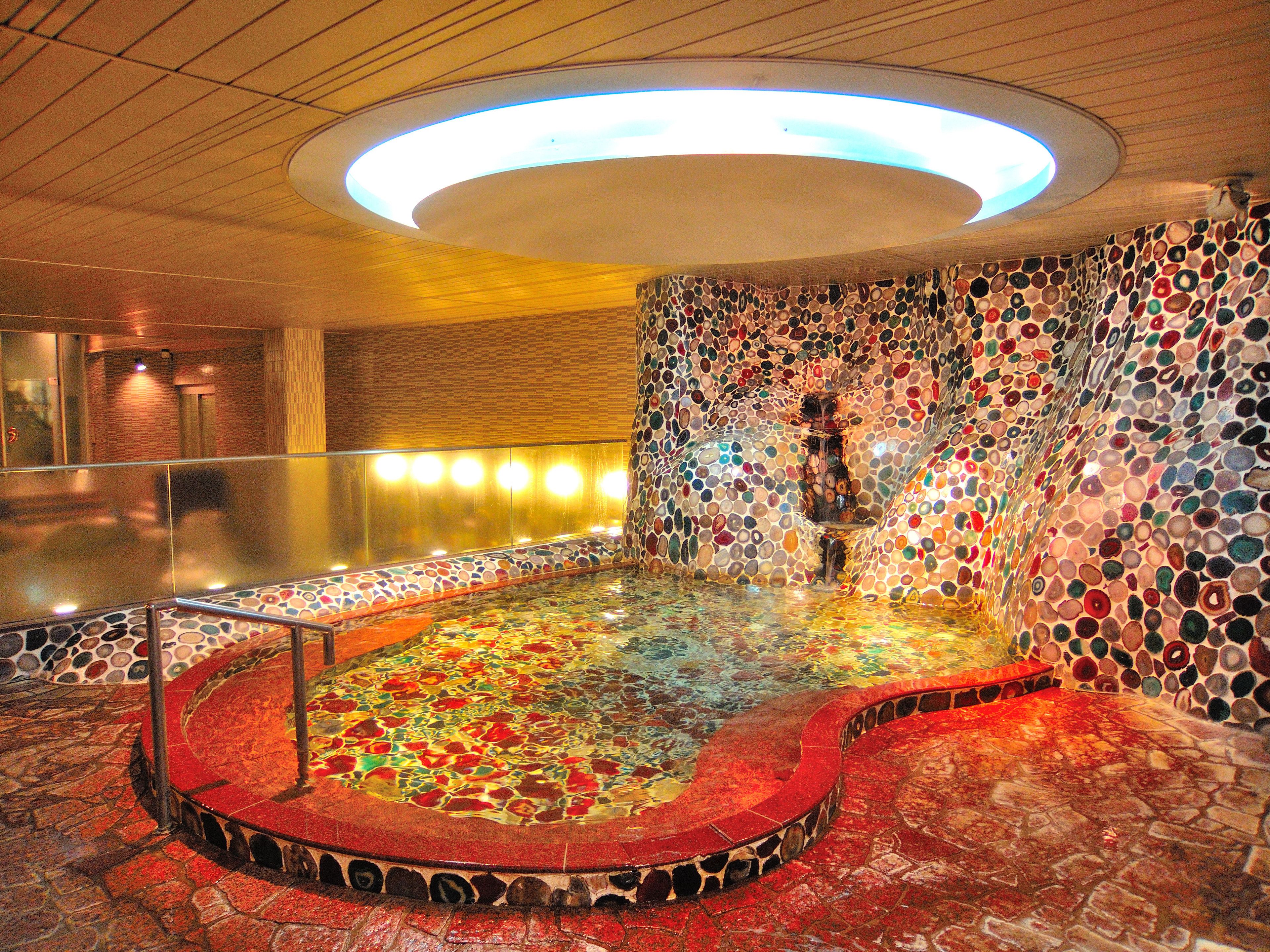 A circular hot tub area with mosaic walls and a wooden ceiling.