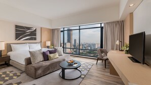 A hotel room with a bed, a sofa, a desk, a television, and a large window offering a city view. - Seda Vertis North Quezon City (Quezon City)